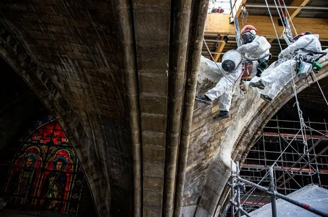 Workmen plaster stonework as they rappel down a vault at the Notre-Dame de Paris Cathedral, which was damaged in a devastating fire two years ago, as restoration works continue in Paris, France, April 15, 2021. (Photo by Ian Langsdon/Pool via Reuters)