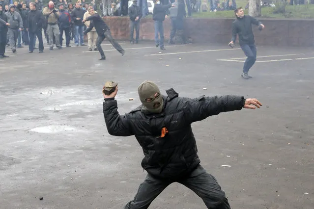 Pro-Russian men throw stones during the mass storming of a police station in Horlivka, eastern Ukraine, Monday, April 14, 2014. Ukraine's acting President Oleksandr Turchynov on Monday called for the deployment of United Nations peacekeeping troops in the east of the country, where pro-Russian insurgents have occupied buildings in nearly 10 cities. (Photo by Efrem Lukatsky/AP Photo)