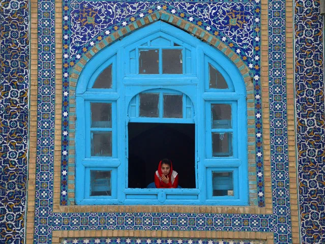 An Afghan girl looks on a window of the Hazrat-e-Ali shrine at Nowruz festivities which mark the Afghan new year in Mazari-i-Sharif on March 21, 2017. Nowruz, one of the biggest festivals of the war-scarred nation, marks the first day of spring and the beginning of the year in the Persian calendar. Nowruz is calculated according to a solar calendar, this coming year marking 1396. (Photo by Farshad Usyan/AFP Photo)