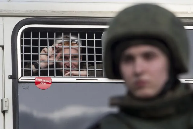 A detained protester looks out of a police bus window with a red sticker reading “Navalny” in downtown Moscow, Russia, Sunday, March 26, 2017. Russia's leading opposition figure Alexei Navalny and his supporters aim to hold anti-corruption demonstrations throughout Russia. But authorities are denying permission and police have warned they won't be responsible for “negative consequences” or unsanctioned gatherings. (Photo by Denis Tyrin/AP Photo)