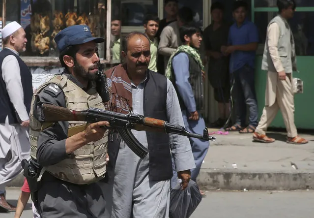 An Afghan policeman stands guard after an explosion near the police headquarters in Kabul, Afghanistan, Wednesday, August 7, 2019. A suicide car bomber targeted the police headquarters in a minority Shiite neighborhood in western Kabul on Wednesday, setting off a huge explosion that wounded dozens of people, Afghan officials said. The Taliban claimed responsibility for the bombing. (Photo by Rafiq Maqbool/AP Photo)
