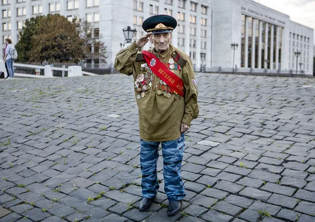 World War II veteran Lev Yatsevich, 92, salutes as he waits for other participants of an event marking the anniversary of the failed August 1991 hard-line coup outside the former Russian parliament building, which now houses Russian Cabinet, in Moscow, Russia, Tuesday, August 20, 2019. The coup, which briefly ousted Soviet leader Mikhail Gorbachev, precipitated the collapse of the Soviet Union. (Photo by Alexander Zemlianichenko/AP Photo)