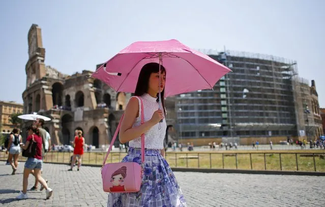 A tourist shelters from the sun as she walks past the Colosseum during a hot summer day in Rome, Italy, July 17, 2015. (Photo by Max Rossi/Reuters)