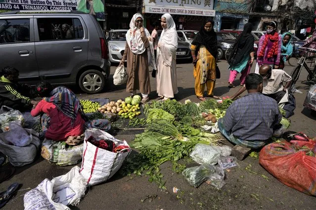 People buy vegetables from a roadside market in Kolkata, India, Tuesday, February 1, 2022. (Photo by Bikas Das/AP Photo)