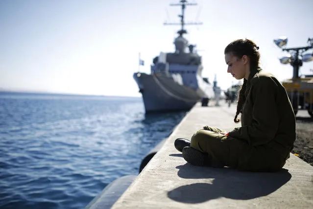 An Israeli soldier sits in front of a naval ship at a navy base in the Red Sea resort city of Eilat March 10, 2014. (Photo by Amir Cohen/Reuters)