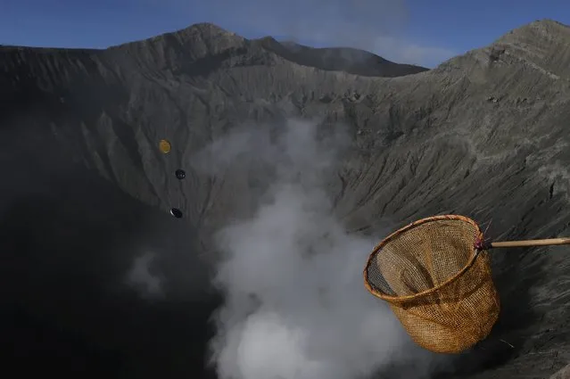 A man holds out a net in an attempt to catch coins thrown as offerings by Hindu worshippers into the crater during the Kasada Festival at Mount Bromo in Probolinggo, Indonesia's East Java province, August 1, 2015. (Photo by Reuters/Beawiharta)