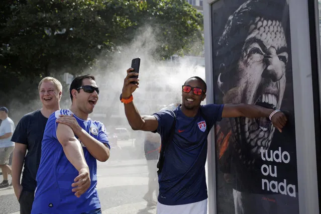 A U.S. soccer fan pretends that Uruguay's soccer striker Luis Suarez is biting him as he takes a selfie next to an Adidas advertisement featuring Suarez near Copacabana beach in Rio de Janeiro, Brazil, Thursday, June 26, 2014. FIFA banned Suarez from all football activities for four months on Thursday for biting an opponent at the World Cup, a punishment that rules him out of the rest of the tournament. (Photo by Matt Dunham/AP Photo)