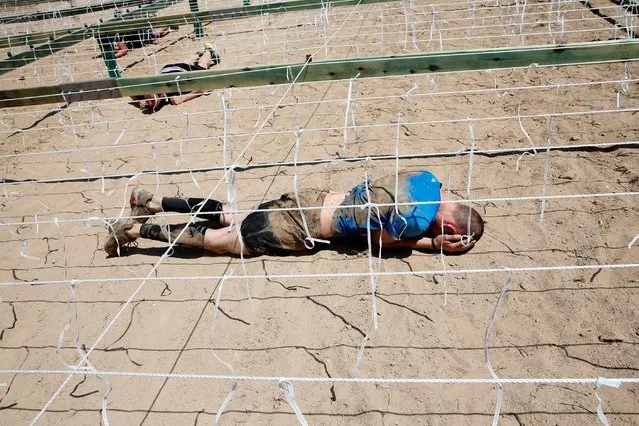 Participants cross the electric shock area as they compete in the Mud Day Race extreme run competition at El Goloso military base, outside Madrid, Spain, June 11, 2016. (Photo by Juan Medina/Reuters)