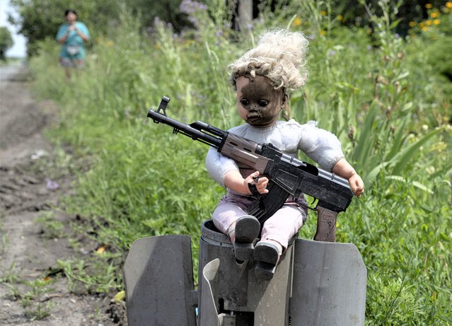 A doll holding a replica of a AK47 gun is set on a tailpiece of a rocket on a roadside in a village near the town of Avdiivka, Donetsk region, on June 28, 2023, amid the Russian invasion of Ukraine. (Photo by Genya Savilov/AFP Photo)