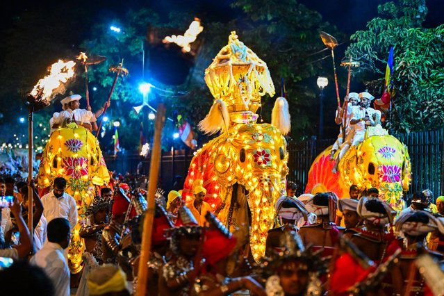 Decorated elephants walk past the historic Buddhist Temple of the Tooth as part of celebrations to mark the Buddhist festival of Esala Perahera, in the ancient hill capital of Kandy, on August 19, 2024. (Photo by Ishara S. Kodikara/AFP)