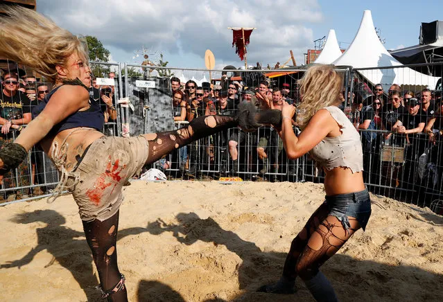 Festivalgoers watch two actors of the Wasteland Warriors movement fight in a cage at the world's largest heavy metal festival, the Wacken Open Air 2019, in Wacken, Germany on August 3, 2019. (Photo by Wolfgang Rattay/Reuters)