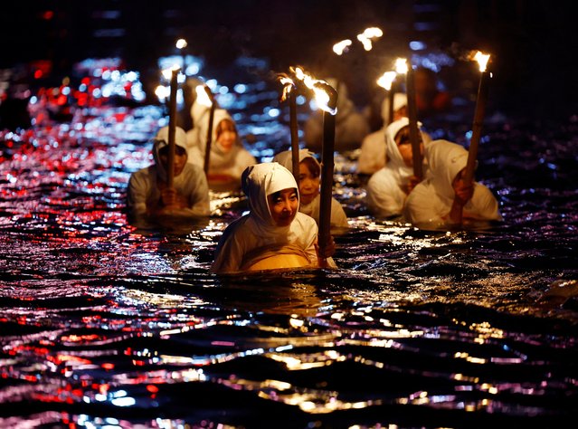 Volunteers in the white-clad of “Ama” female free divers, who harvest sea life from the ocean, swim with torches during Shirahama Ama matsuri in Minamiboso, Chiba Prefecture, Japan on July 20, 2024. (Photo by Kim Kyung-Hoon/Reuters)