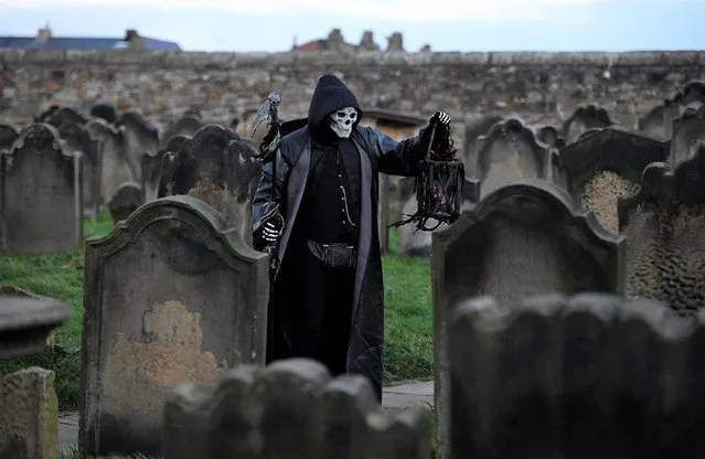 A participant in costume stands amongst gravestones at St Mary the Virgin's church during the biannual “Whitby Goth Weekend” festival in Whitby, northern England, on October 31, 2021. The festival brings together thousands of goths and alternative lifestyle fans from the UK and around the world for a weekend of music, dancing and shopping. (Photo by Oli Scarff/AFP Photo)