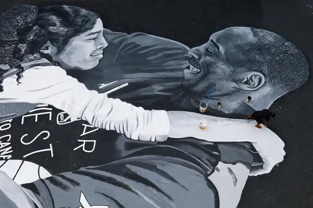 A man polishes the mural in memory of Kobe Bryant and his daughter Gianna, painted hours after they died in a helicopter crash, on the basketball court of a housing tenement in Taguig City, Metro Manila, Philippines, January 28, 2020. (Photo by Eloisa Lopez/Reuters)