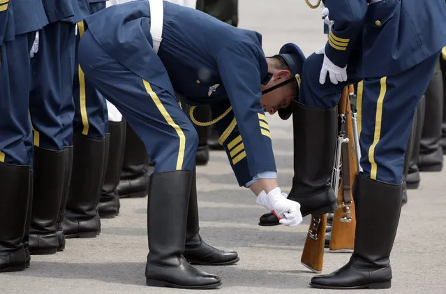 A member of an honor guard wipes the shoes of another as they prepare for a welcome ceremony  at Beijing airport. (Photo by Jason Lee/Reuters)