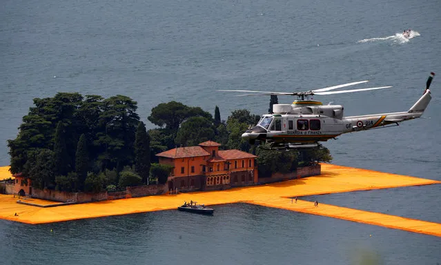 A helicopter of Italy's fiscal police “Guardia di Finanza” flies over the installation “The Floating Piers” by Bulgarian-born artist Christo Vladimirov Yavachev, known as Christo, at the installation's last weekend near Sulzano, northern Italy, July 2, 2016. (Photo by Wolfgang Rattay/Reuters)