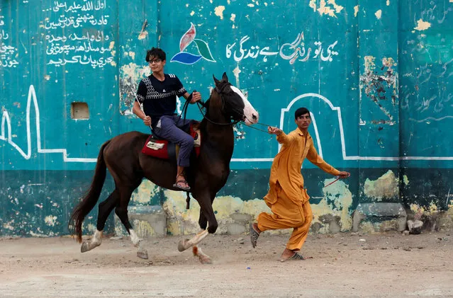 A trainer guides a boy to learn horse riding along a street in Karachi, Pakistan June 24, 2017. (Photo by Akhtar Soomro/Reuters)