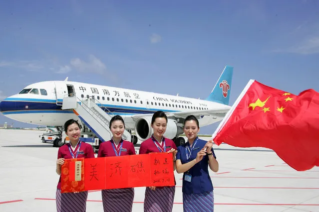 Crew members holding a Chinese national flag pose for pictures in front of a plane of the China Southern Airlines as the plane landed at a new airport China built on Mischief Reef of the Spratlys, South China Sea, July 13, 2016. (Photo by Reuters/Stringer)
