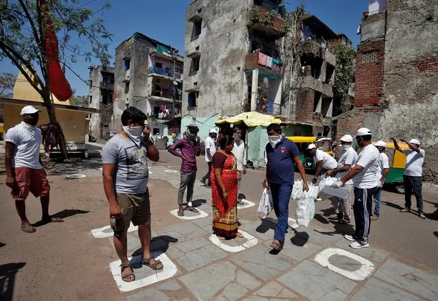 Municipal workers distribute bags of food amongst the residents as they maintain safe distance during a 21-day nationwide lockdown to limit the spreading of coronavirus disease (COVID-19), in Ahmedabad, India, March 29, 2020. (Photo by Amit Dave/Reuters)