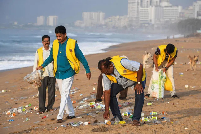 Volunteers pick up trash from a sea beach during a beach clean-up campaign organised by the government of Andhra Pradesh in association with “Parley for the Oceans” a member of the Global Alliance for a Sustainable Planet that planned a beach clean-up programme on a stretch of 30 kilometres with over 20,000 volunteers in Visakhapatnam on August 26, 2022. (Photo by Noah Seelam/AFP Photo)