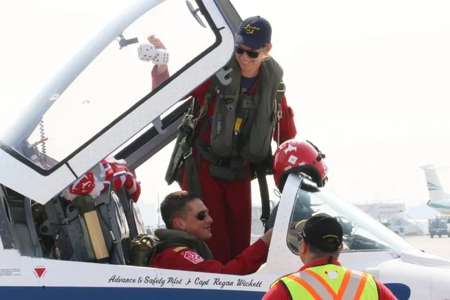 Snowbird Pilot Captain Regan Wickett smiles as pilot Lieutenant Patricia Brunelle removes a pair of fuzzy dice from the cockpit of a CT144 Tutor Snowbird jet during media day for the Canadian International Air Show at Pearson Airport in Toronto, Ontario, September 3, 2015. (Photo by Louis Nastro/Reuters)