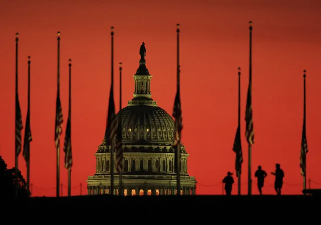 The U.S. Capitol dome backdrops flags at half-staff in honor of the victims killed in the Las Vegas shooting as the sun rises on Tuesday, October 3, 2017, at the foot of the Washington Monument on the National Mall in Washington. (Photo by Manuel Balce Ceneta/AP Photo)