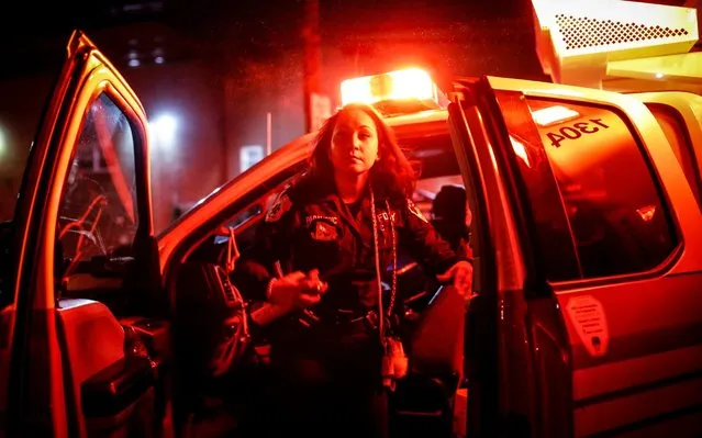 FDNY paramedic Elizabeth Bonilla sprays herself with disinfectant after responding to an emergency call during the coronavirus outbreak Wednesday, April 15, 2020, in the Bronx borough of New York. “Emotionally, you have to be strong for the families that are going through it”, she said. “You don't want to cry in front of them. You want to show them that you're strong and you're there to support them”. (Photo by John Minchillo/AP Photo)