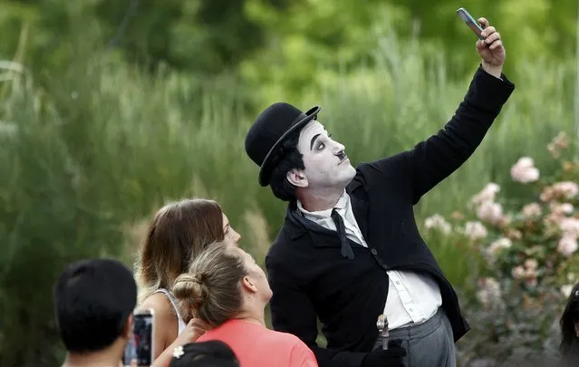 A street entertainer dressed as Charlie Chaplin takes a selfie with a passer-by on the  Southbank in central London, Britain July 31, 2016. (Photo by Peter Nicholls/Reuters)