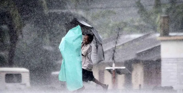 A village boy holds an umbrella and walks in the rain with another, wrapped in a plastic sheet, on the outskirts of Bhubaneswar, India, Wednesday, September 10, 2014. (Photo by Biswaranjan Rout/AP Photo)