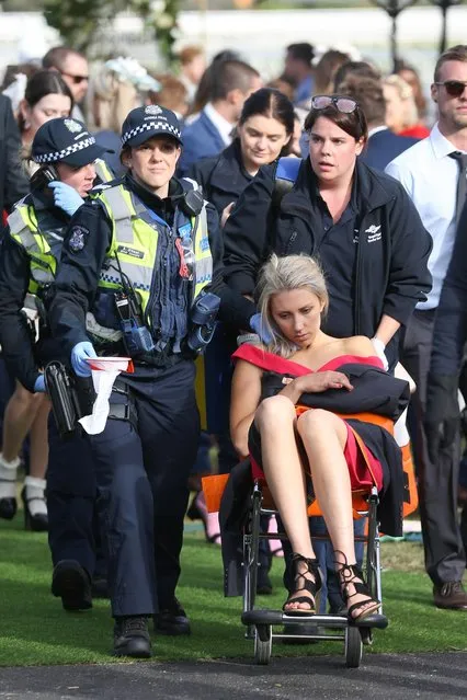 A woman is taken to safety in a wheelchair during Caulfield Cup Day at Caulfield Racecourse on October 21, 2017 in Melbourne, Australia. (Photo by Splash News and Pictures)
