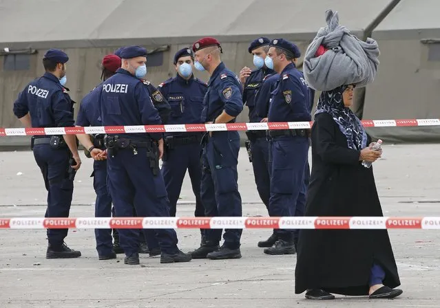 A migrant woman carries her belongings as she passes by policemen at the border crossing with Hungary in Nickelsdorf, Austria September 15, 2015. Fewer migrants crossed into Austria from Hungary on Tuesday after Budapest started to clamp down on the flow through the Balkan peninsula to the richer countries of northern and western Europe, Austrian police said. (Photo by Leonhard Foeger/Reuters)