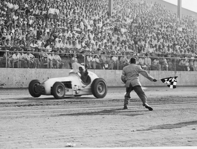 Jimmy Bryan of Phoenix, Ariz., gets the checkered victory flag at the Indiana State Fairgrounds September 17, 1955 as he wins the “Hoosier Hundred” for the second consecutive year. Bryan averaged 83.98 miles an hour for the 100-lap, 100-mile AAA big car race. (Photo by AP Photo)