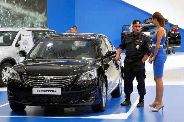 A police officer speaks with a model representing a Changan Raeton car during the 2016 Moscow International Auto Salon in Moscow, Russia, August 26, 2016. (Photo by Sergei Karpukhin/Reuters)