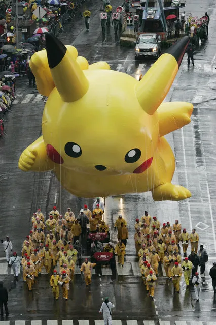 The Pikachu balloon floats down Broadway in the rain during the Macy's Thanksgiving Day parade in New York, Thursday, November 23, 2006. (Photo by Jeff Christensen/AP Photo)
