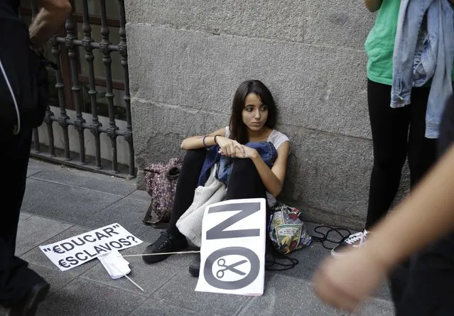 A demonstrator with banners sits on the ground during a protest on the second day of a nationwide student strike against rising fees and educational cuts in Madrid, October 22, 2014. Banner reads “To educate Slaves?”. (Photo by Andrea Comas/Reuters)