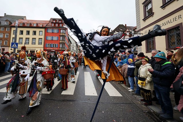 A carnival reveller swings around a long wooden stick and performs a vault, the so-called “Fools Jump”, during the traditional folklore procession “Narrensprung” dating back to the 14th century as part of the Swabian-Alemannic Rose Monday celebrations in the Black Forest town of Rottweil, in south-western Germany, on February 12, 2024. (Photo by Wolfgang Rattay/Reuters)