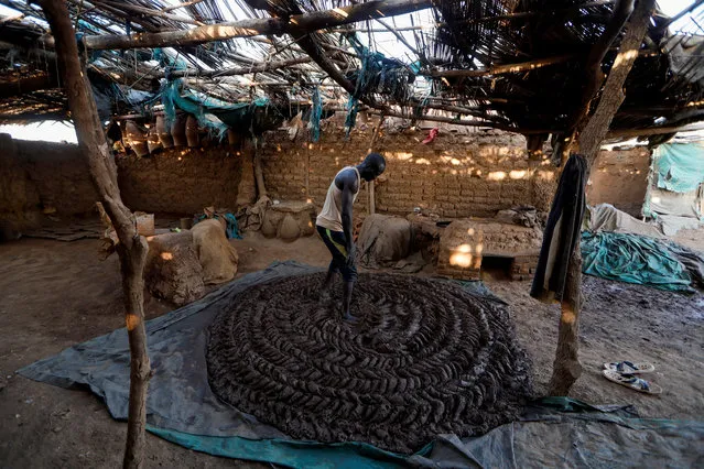 David Plantino, 35, a pottery maker from South Sudan, kneads mud with his feet, that will be used to make pottery at a workshop in an area known as the “Potters Village” in Alqamayir, Omdurman, Sudan  February 16, 2020. “I have been a pottery maker for 7 years, I relied on the Nile river like most people around me here for water and the mud”, Plantino said. “Both are the foundation for people who rely on pottery to make a living”. (Photo by Zohra Bensemra/Reuters)