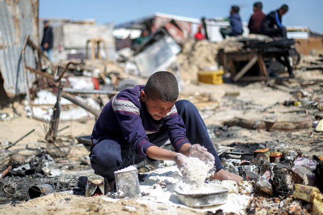 A boy salvages flour in the aftermath of a reported Israeli strike on a tent shelter in Khan Yunis in the southern Gaza Strip on April 17, 2025. Gaza's civil defence agency said on April 17 that Israeli air strikes hit multiple encampments for displaced civilians, killing at least 25 people as it pressed its unrelenting military offensive in the Palestinian territory. Israel had resumed its intense military offensive in the Palestinian territory after a ceasefire deal that came into effect on January 19 fell apart two months later over differences regarding its next phase. (Photo by Eyad Baba/AFP Photo)