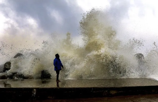 A person watches as gusty winds and high waves lash on an embankment in Chennai, India, Friday, December 9, 2022. India's southern Tamil Nadu state is bracing for heavy rain as cyclone Mandous is set to cross near the Chennai coast overnight on Friday. (Photo by R.Parthibhan/AP Photo)