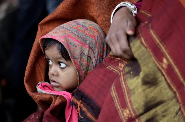 A girl wrapped in a shawl looks on as she waits along with her mother for a train at a railway station on a cold winter morning in New Delhi, January 3, 2018. (Photo by Saumya Khandelwal/Reuters)