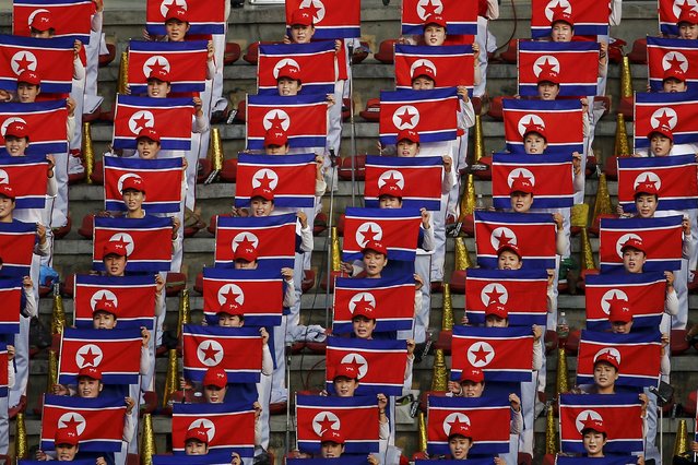 North Korean fans hold flags and sing the national anthem before their team's preliminary 2018 World Cup and 2019 AFC Asian Cup qualifying soccer match against Philippines at the Kim Il Sung Stadium in Pyongyang October 8, 2015. (Photo by Damir Sagolj/Reuters)