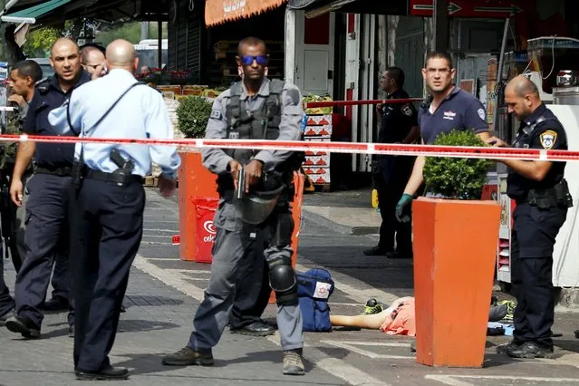 Israeli police secure the area as they stand next to the body of a dead Palestinian assailant at the spot where he stabbed two Israeli Jews before was shot dead outside Jerusalem's Old City October 10, 2015. Israeli forces shot dead two Palestinian assailants in East Jerusalem on Saturday, one of whom had stabbed two Israelis, police said, in a wave of violence that has raised concerns about a new Palestinian uprising. (Photo by Ammar Awad/Reuters)