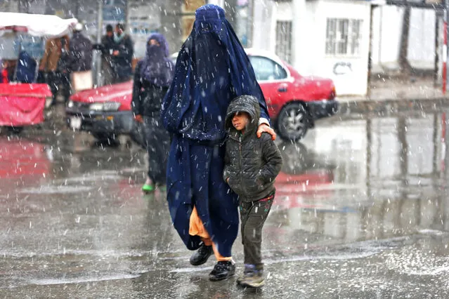Commuters make their way along a street during snowfall in Kabul on December 29, 2022. (Photo by AFP Photo/Stringer)