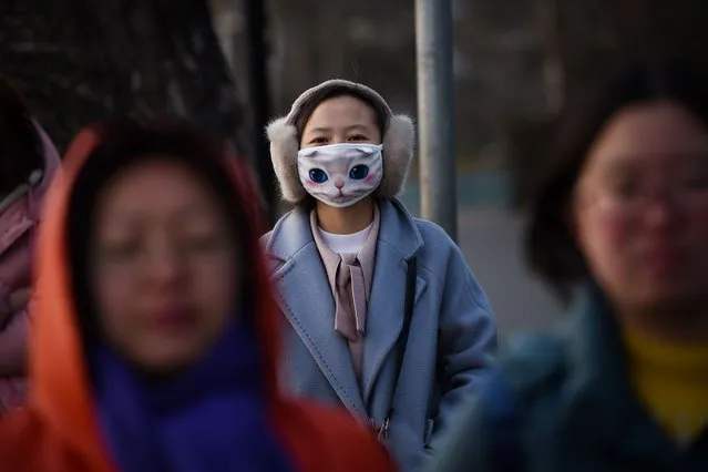 A woman wears a mask with a cat pattern as she walks a long a road in Beijing on January 15, 2018. (Photo by Wang Zhao/AFP Photo)