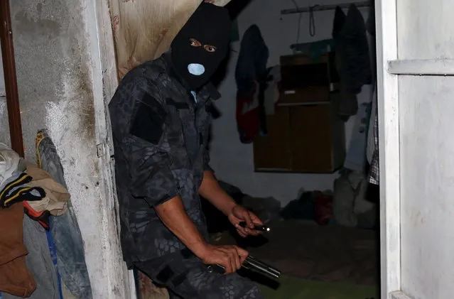 An officer of a Libyan anti-illegal immigrants unit conducts an early morning raid on migrants at hideout in Tripoli, Libya, October 13, 2015. (Photo by Hani Amara/Reuters)