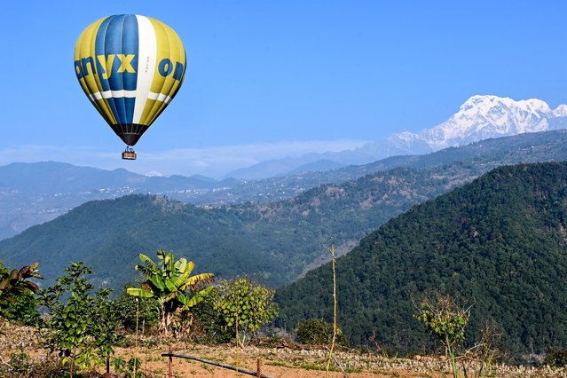 A hot air balloon rises in the sky during the International Hot-Air Balloon festival in Pokhara on December 27, 2024. With Nepal's snowy Himalayan peaks as a backdrop, the sky above Pokhara transformed into a vibrant canvas of colours for the country's first hot-air balloon festival. (Photo by Prakash Mathema/AFP Photo)