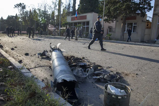 Members of Azerbaijan's security forces, walk past remains of a missile, as they inspect the damage following an overnight missile attack by Armenian forces, in the city of Ganja, Azerbaijan's second-largest city, Thursday, October 8, 2020. The fighting between Armenian and Azerbaijani forces over the separatist territory of Nagorno-Karabakh, continued with both sides accusing each other of launching attacks. The region lies in Azerbaijan but has been under the control of ethnic Armenian forces backed by Armenia since the end of a separatist war in 1994. (Photo by Unal Cam/DHA via AP Photo)