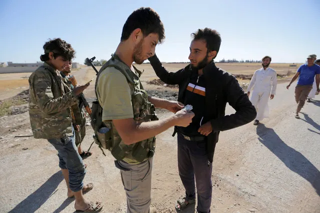 Rebel fighters of 'Al-Sultan Murad' brigade inspect the identification papers of men who fled from Islamic State-controlled areas, upon their arrival at a checkpoint in the northern Syrian rebel-held town of al-Rai, in Aleppo Governorate, Syria, September 28, 2016. (Photo by Khalil Ashawi/Reuters)