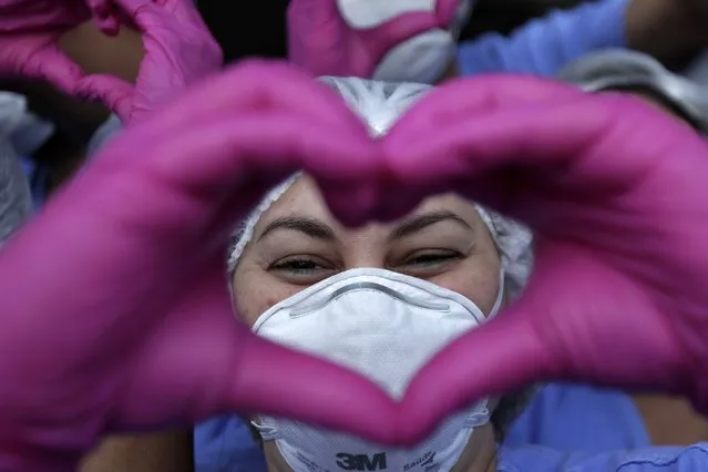 A health worker makes a heart sign while she and her fellow workers celebrate as the last three patients are released from a field hospital at the National Stadium Mane Garrincha, after recuperating from COVID-19, in Brasilia, Brazil, Thursday, October 15, 2020. (Photo by Eraldo Peres/AP Photo)