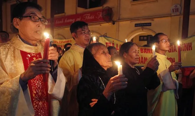 Peter Doan Van Vuon's mother Mary Tran Thi Map (front row, L) and her daughter Teresa Doan Thi Map hold candles while praying for the release of her son and grandsons, before their trial next week, during Easter mass at Thai Ha church in Hanoi March 31, 2013. The case of Vuon's family in Vietnam's northern Hai Phong port city, who used landmines and guns to stop local officials from seizing their land in January 2012, has sparked rare open criticism of the authorities' strong-arm approach. Six police and soldiers had been injured in the clash, and four people – Van Vuon, his brother and two other relatives – were arrested. (Photo by Kham/Reuters)